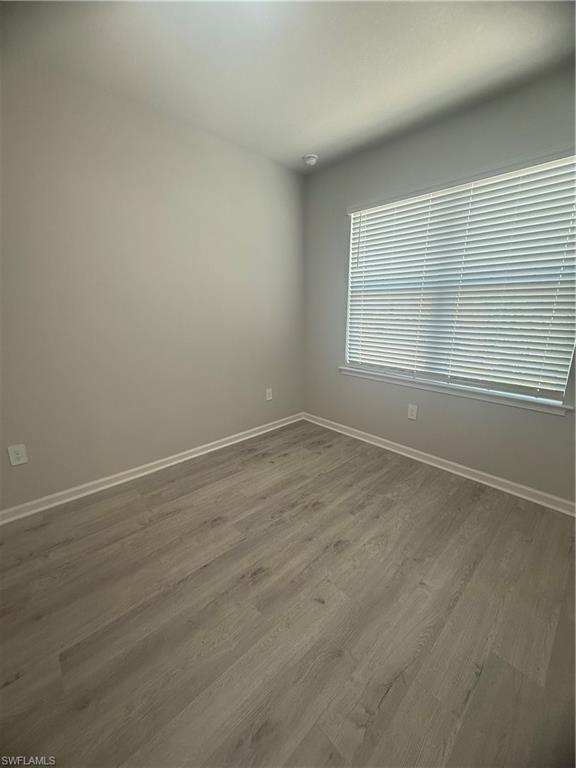 4551 Arboretum Circle, Unit 203 Naples, FL 34112 - Photo 23 of 41 an empty room with wooden floor and windows