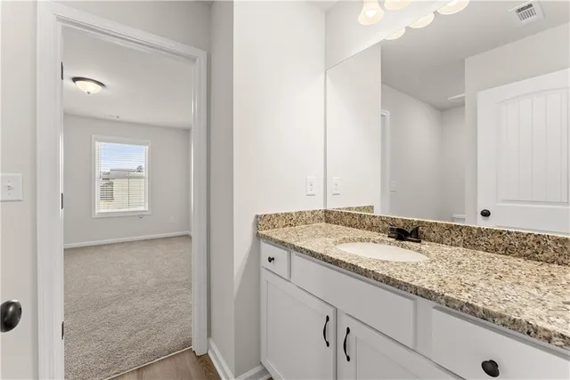 a bathroom with a granite countertop sink and a mirror