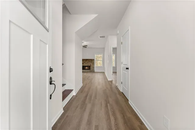 a view of a hallway with wooden floor and a large mirror