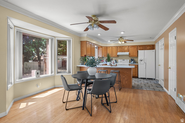 1726 Wasatch Boulevard Sandy, UT 84092 - Photo 6 of 38 Open-concept kitchen and dining area featuring a bay window, wood-finish flooring, two ceiling fans, wood cabinetry, and a kitchen island with seating