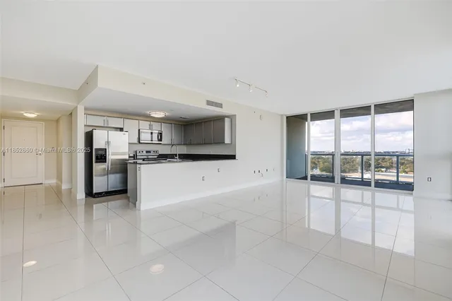 a large white kitchen with a stove a sink and a large window