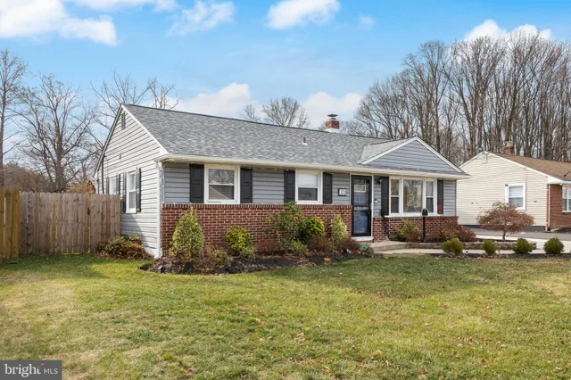 a front view of a house with a yard outdoor seating and covered with trees