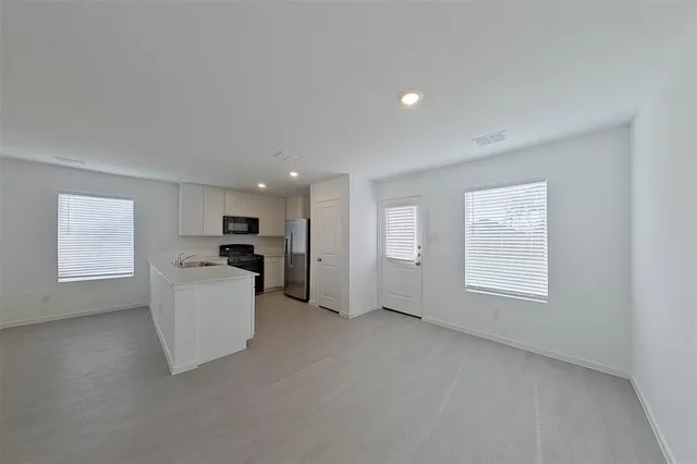 a view of empty room with kitchen and window