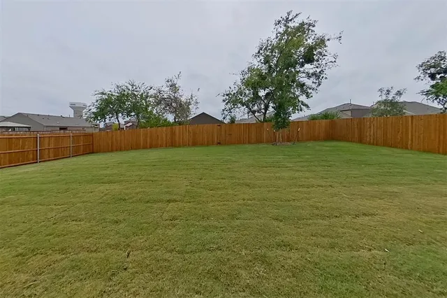 a view of yard with swimming pool and wooden fence
