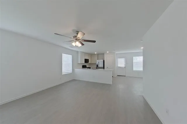 a view of a livingroom with a chandelier fan and windows