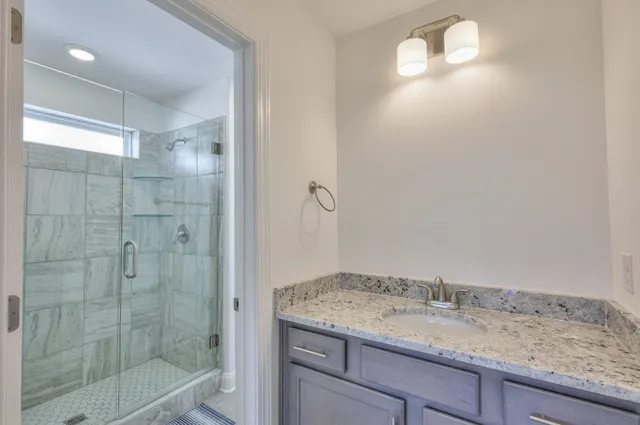 a bathroom with a granite countertop sink a mirror and shower