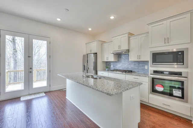 a kitchen with stainless steel appliances granite countertop a stove a sink and a microwave