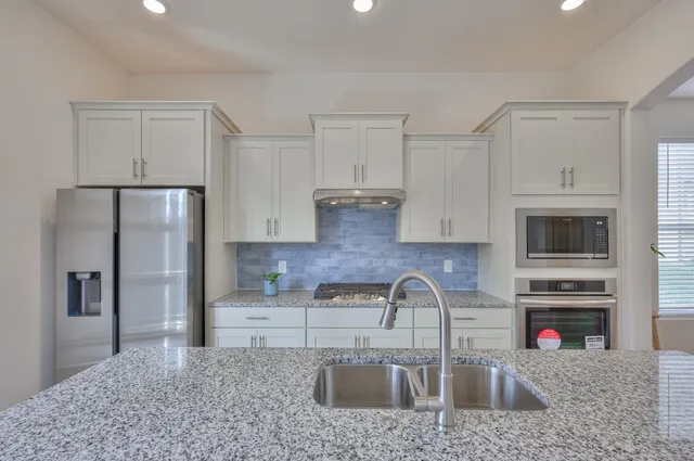 a kitchen with stainless steel appliances granite countertop a refrigerator sink and cabinets