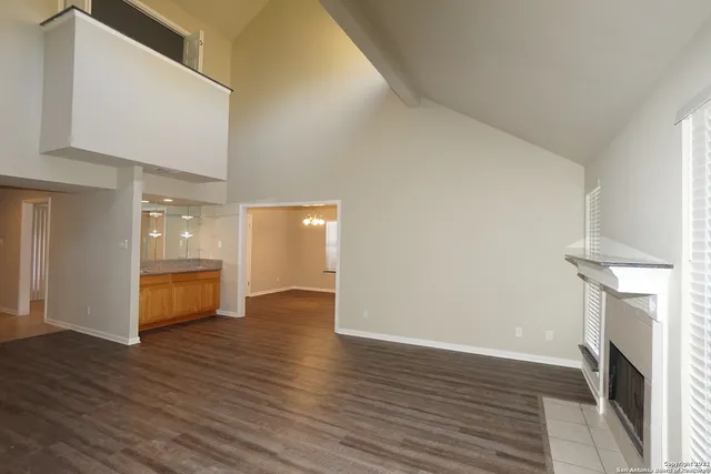 a view of an empty room with wooden floor fireplace and a window