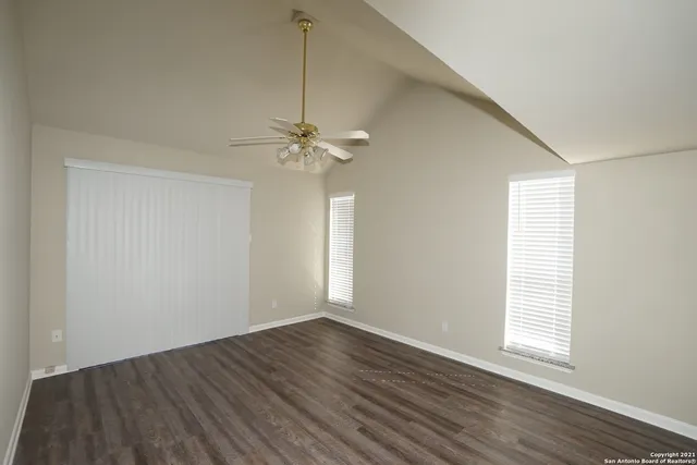 a view of an empty room with wooden floor and a window