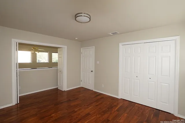 a view of empty room with wooden floor and fan