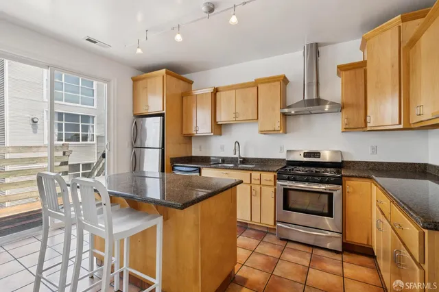 a kitchen with stainless steel appliances granite countertop a stove top oven a sink a dining table and chairs