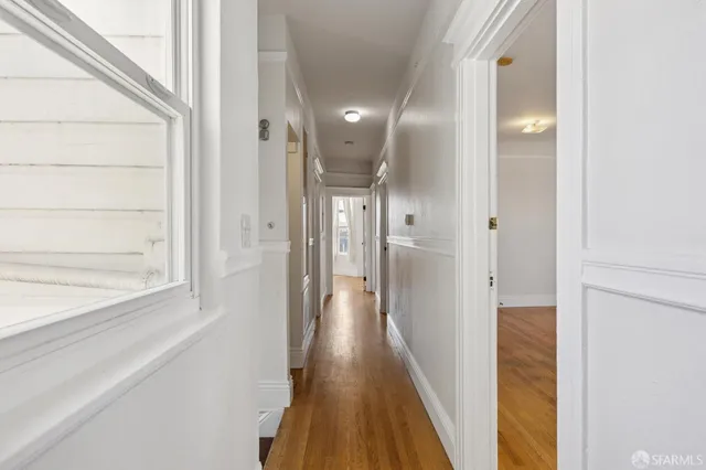 a view of a hallway with wooden floor and staircase