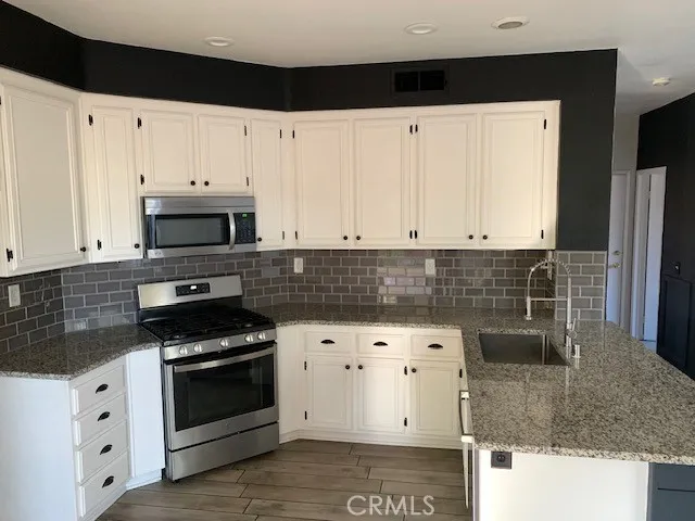 a kitchen with granite countertop white cabinets and stainless steel appliances
