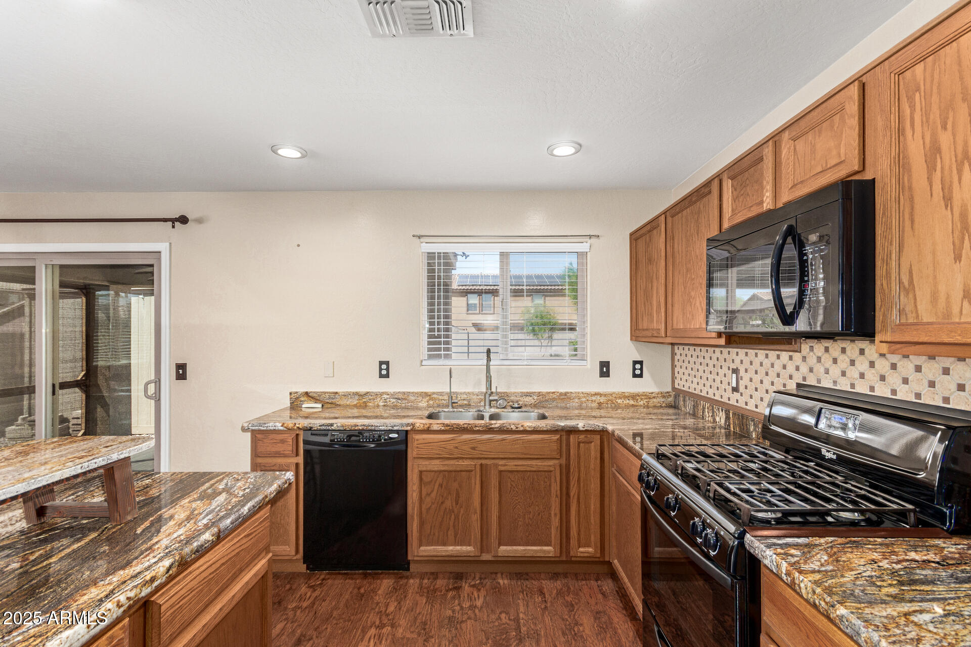 40214 West Lococo Street Maricopa, AZ 85138 - Photo 3 of 31 a kitchen with stainless steel appliances granite countertop a stove a sink dishwasher and a microwave oven with large trees