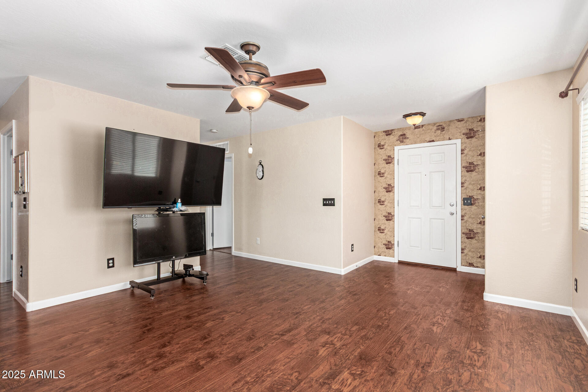 40214 West Lococo Street Maricopa, AZ 85138 - Photo 7 of 31 a view of a livingroom with a flat screen tv wooden floor and a ceiling fan