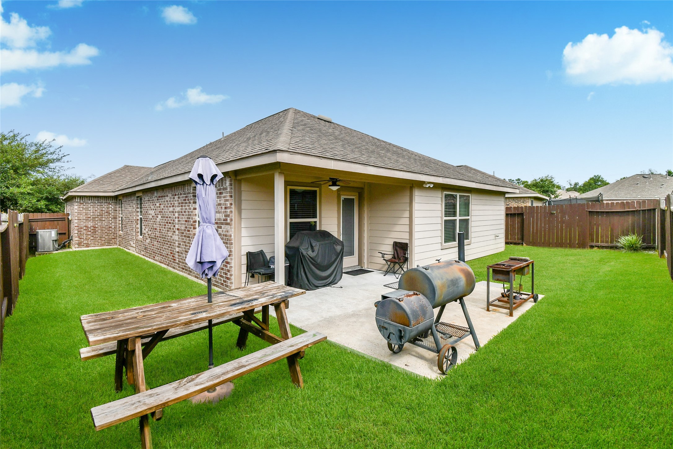 652 Maple Point Drive East Conroe, TX 77301 - Photo 29 of 35 This backyard features a well-maintained lawn, a covered patio with seating, a barbecue grill, and a picnic table, all enclosed by a wooden fence for privacy.