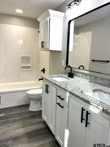 a bathroom with a granite countertop toilet sink and mirror