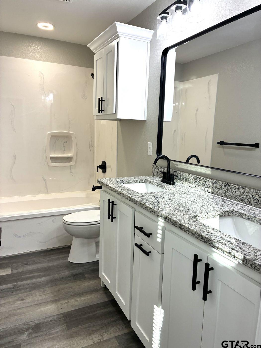 1607 North Ross Avenue Tyler, TX 75702 - Photo 5 of 10 a bathroom with a granite countertop toilet sink and mirror