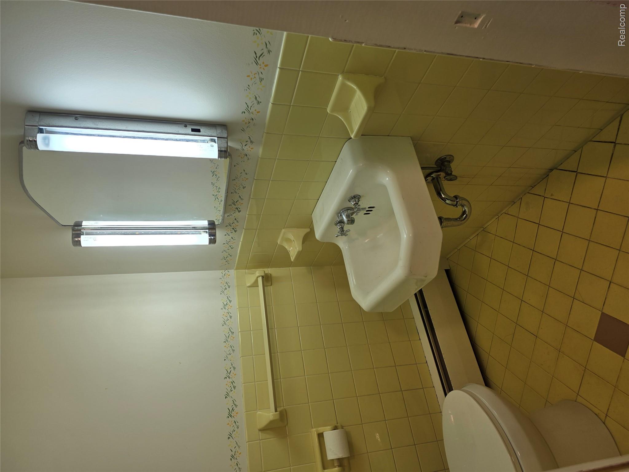 403 East Road Holly, MI 48442 - Photo 18 of 22 Half bath featuring wainscoting, tile walls, baseboard heating, and light tile patterned floors