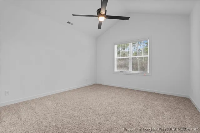 an empty room with ceiling fan and windows