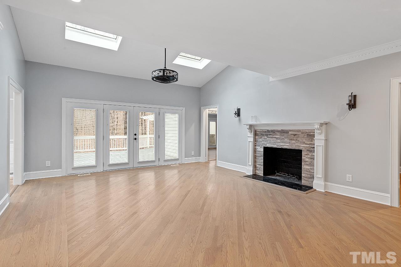 9132 Sutherland Court Raleigh, NC 27615 - Photo 15 of 36 a view of an empty room with wooden floor fireplace and a window