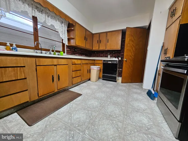 a kitchen with stainless steel appliances granite countertop a refrigerator a stove and a sink with wooden floor