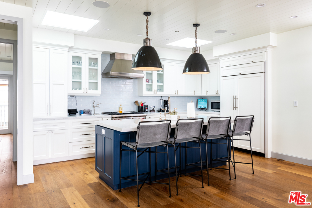 703 Bayview Drive Manhattan Beach, CA 90266 - Photo 7 of 30 a open kitchen with stainless steel appliances granite countertop a stove a sink dishwasher a dining table and chairs with wooden floor