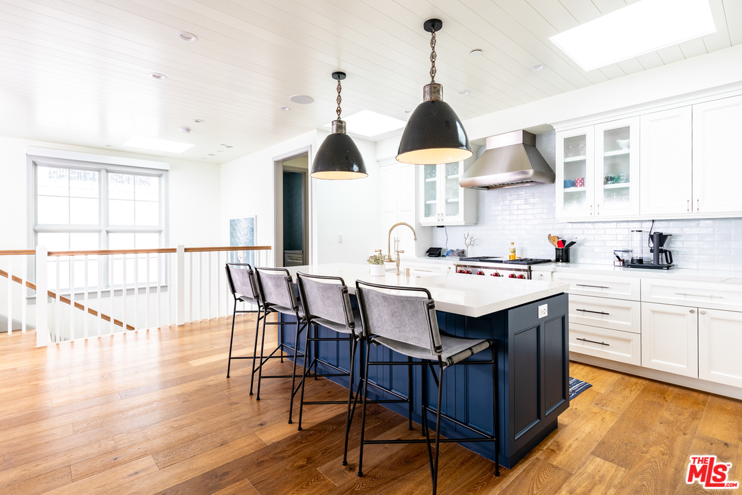 703 Bayview Drive Manhattan Beach, CA 90266 - Photo 9 of 30 a kitchen with stainless steel appliances a sink a stove a dining table and chairs with wooden floor