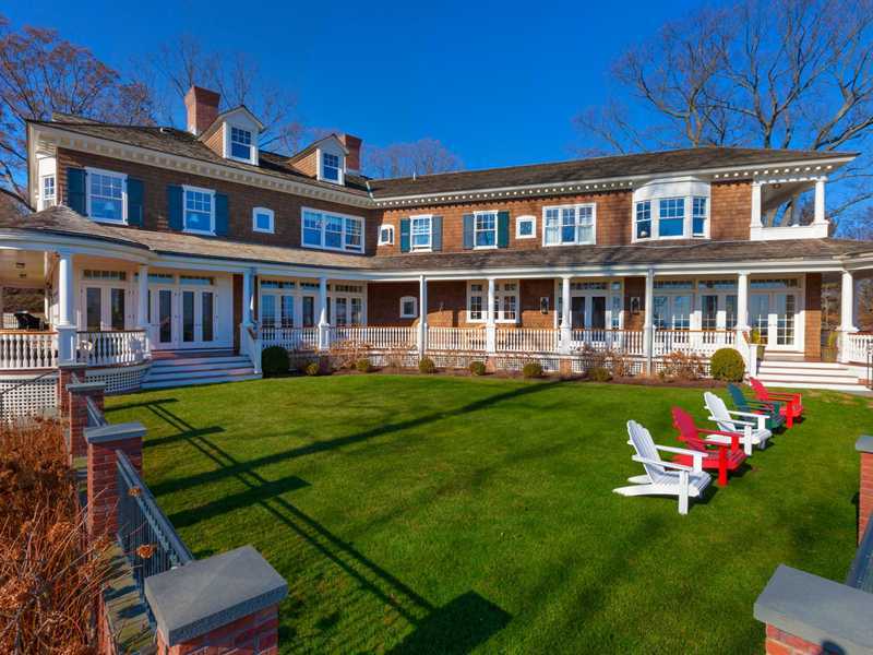 107 Long Neck Point Road Darien, CT 06820 - Photo 3 of 25 a front view of a house with a yard table and chairs