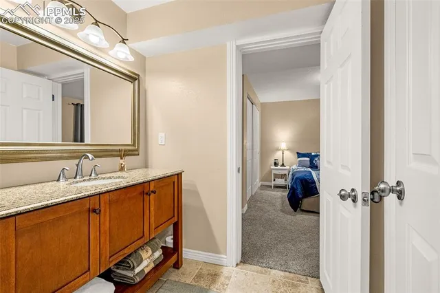 a en suite bathroom with a granite countertop sink and a mirror