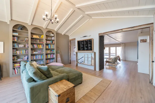 a dining room with wooden floor a chandelier a wooden table and chairs