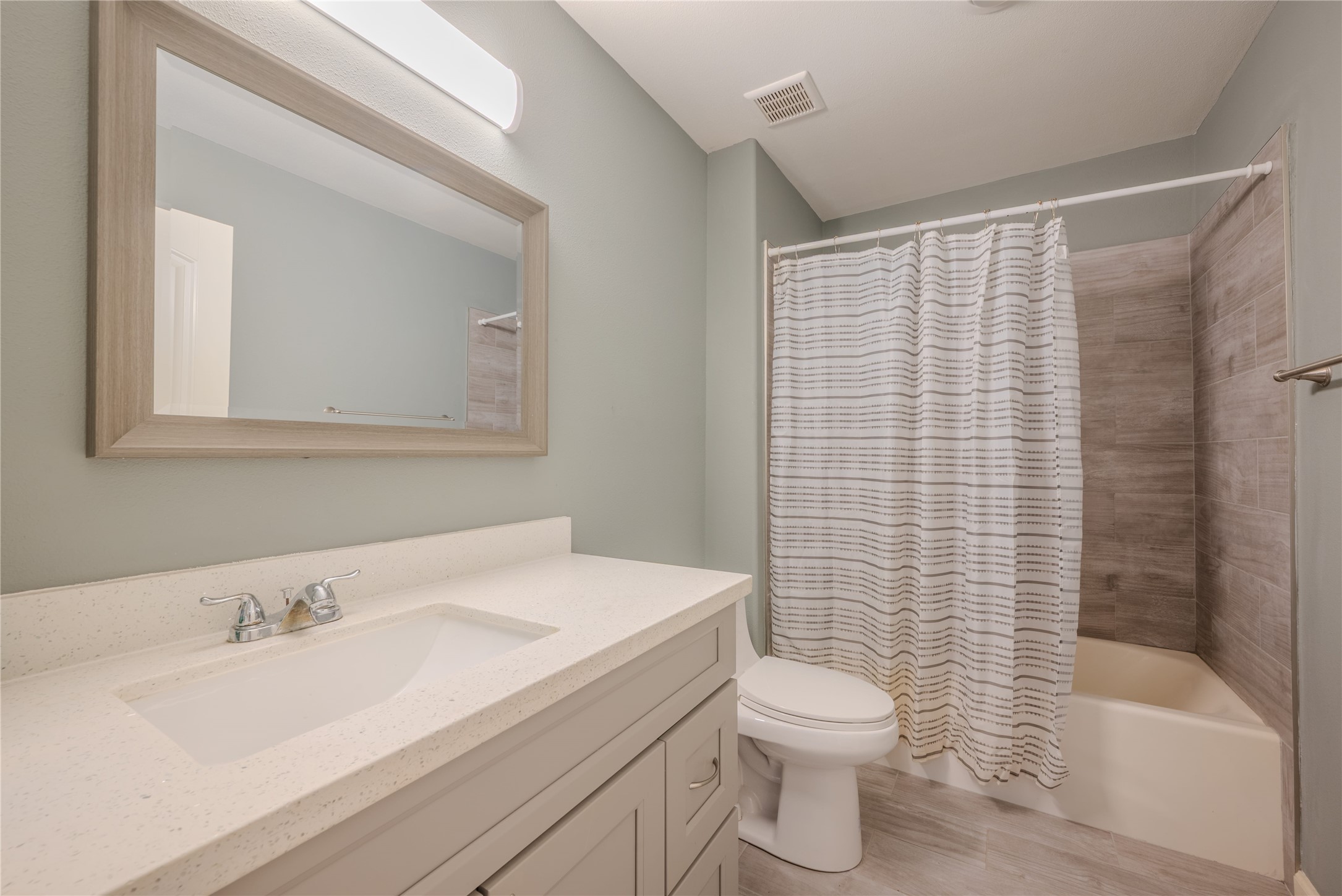 4340 Highway 60 Wharton, TX 77488 - Photo 20 of 49 This bathroom showcases a beautiful vanity and a tub-shower combo with tile work that perfectly mirrors the elegant flooring.