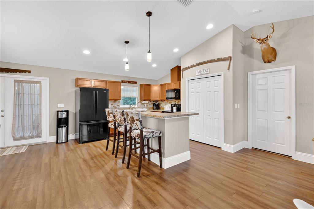 396 North Post Office Road Kenansville, FL 34739 - Photo 7 of 34 a kitchen with stainless steel appliances kitchen island granite countertop a refrigerator a oven a stove top oven and a dining table with wooden floor
