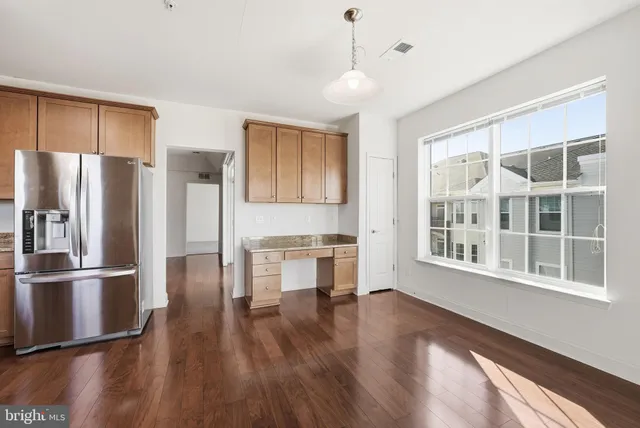 a kitchen with stainless steel appliances granite countertop a refrigerator a stove and a wooden floors