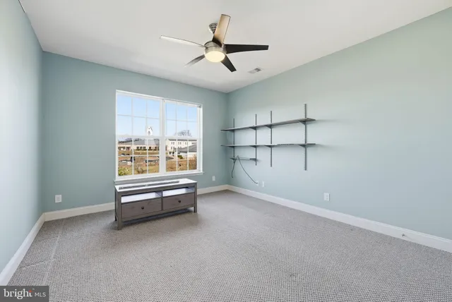an empty room with windows and ceiling fan