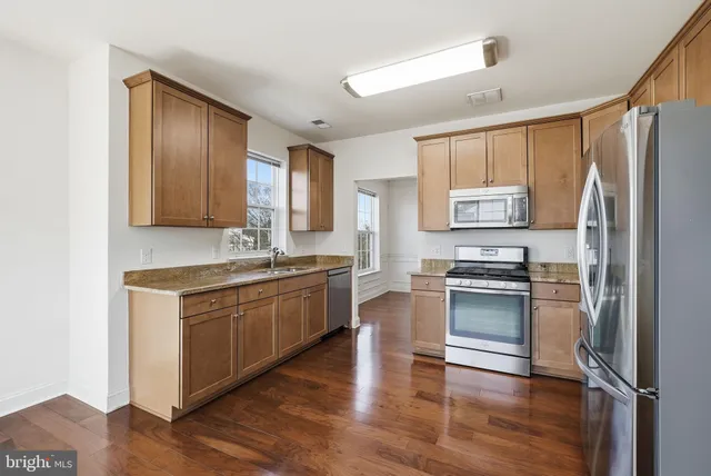 a kitchen with stainless steel appliances granite countertop a refrigerator a stove top oven and sink