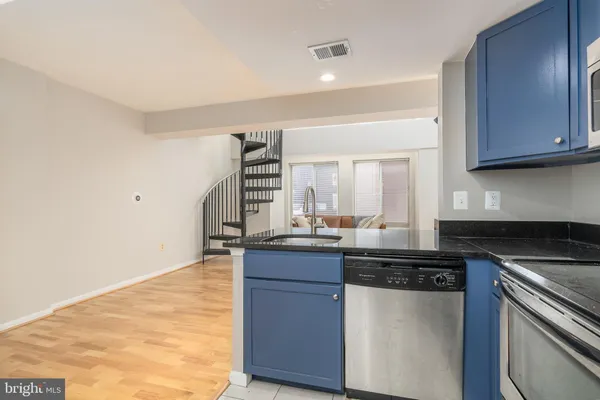 a kitchen with kitchen island granite countertop a sink cabinets and stainless steel appliances