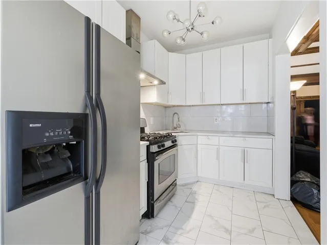 a kitchen with a refrigerator and white cabinets