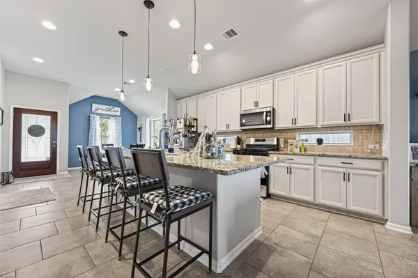 a kitchen with a dining table chairs stainless steel appliances and cabinets