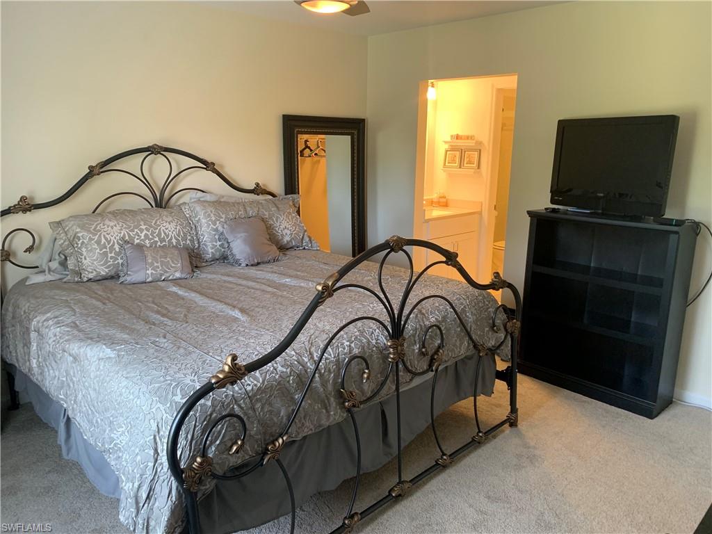 5739 Whitaker Road, Unit A203 Naples, FL 34112 - Photo 8 of 20 a bedroom with a bed and a flat screen tv