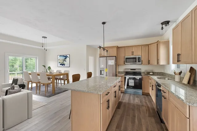 a kitchen with stainless steel appliances granite countertop a stove top oven a sink dishwasher a dining table and chairs with wooden floor