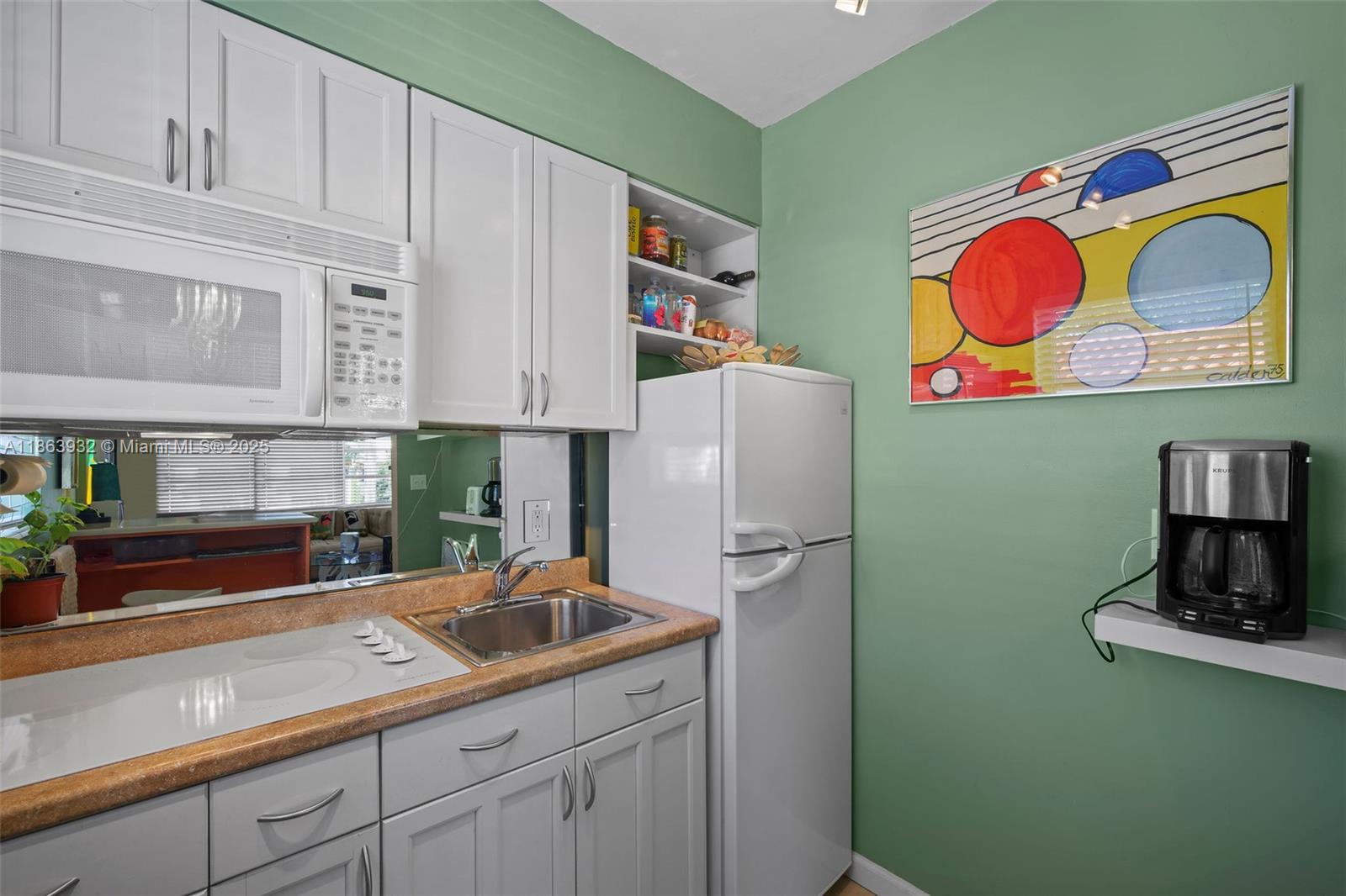 1525 Meridian Avenue, Unit 202 Miami Beach, FL 33139 - Photo 8 of 23 a kitchen with stainless steel appliances granite countertop a sink and a microwave