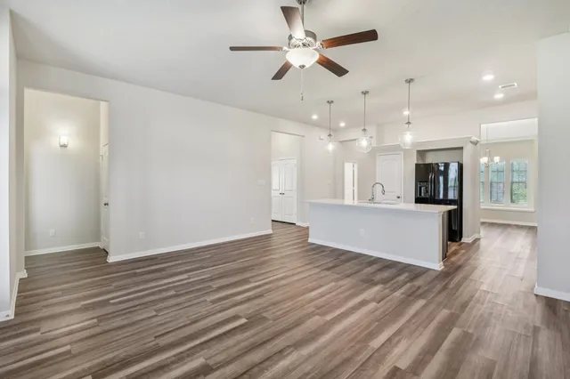 an empty room with wooden floor and a kitchen
