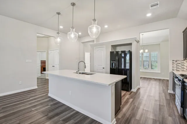 a large kitchen with kitchen island a stove a sink a center island and wooden floor