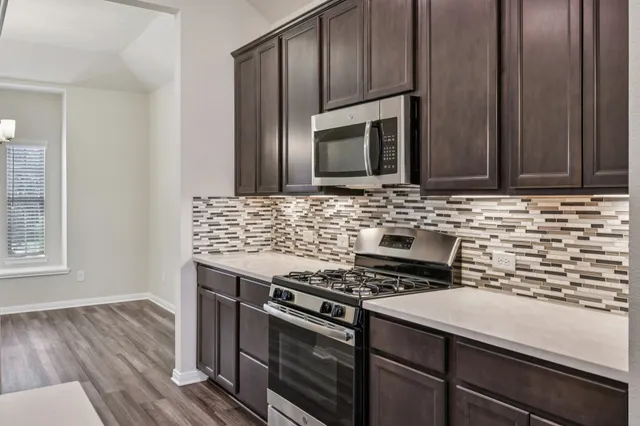 a kitchen with a sink stainless steel appliances and chandelier