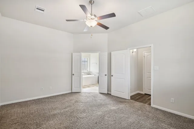 an empty room with windows and fan