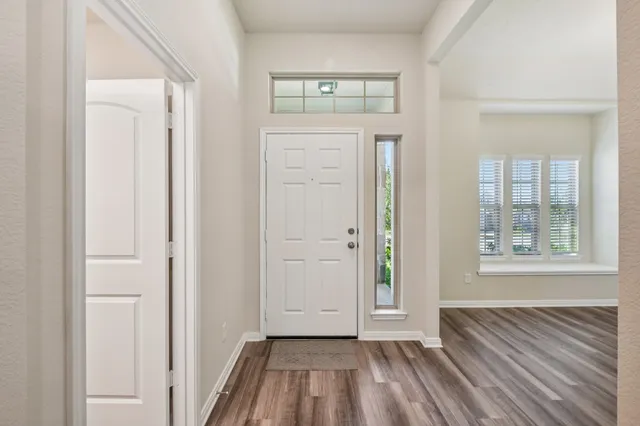 an empty room with wooden floor cabinet and windows