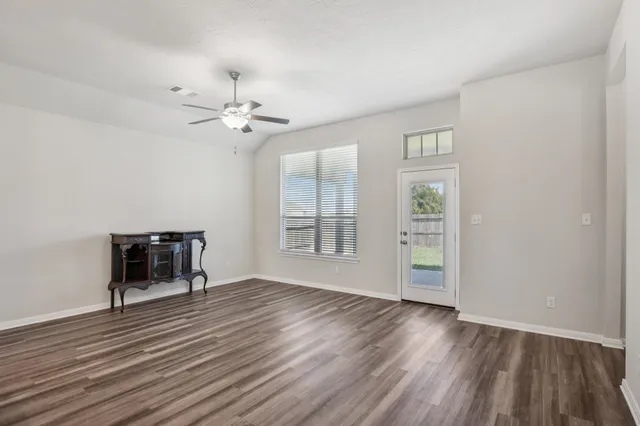 an empty room with windows and ceiling fan