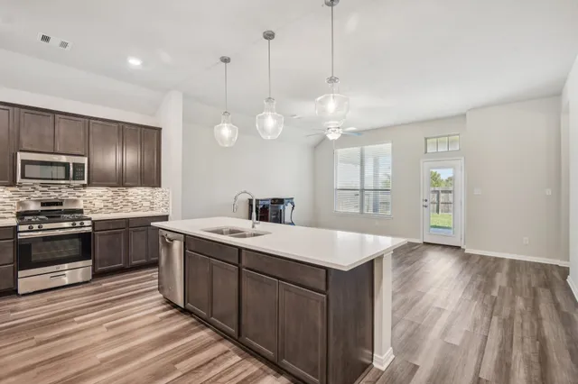 a large kitchen with a large center island a sink stainless steel appliances and cabinets